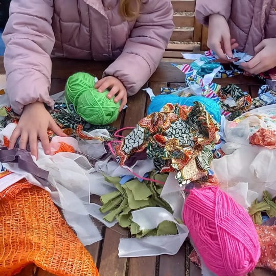 Picture of peoples hands and craft materials on a wooden table.