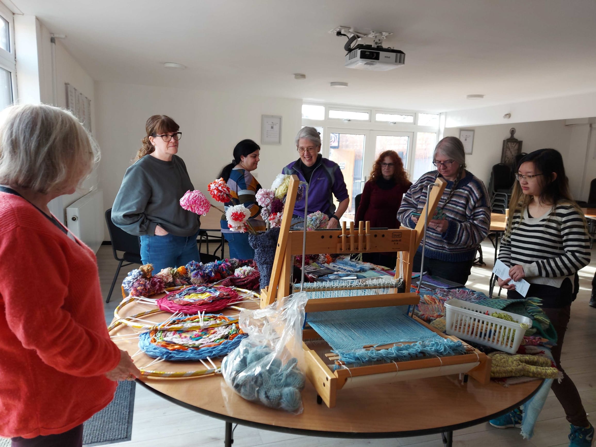 People around a table working with weaving materials at The Making of Coventry weaving workshop